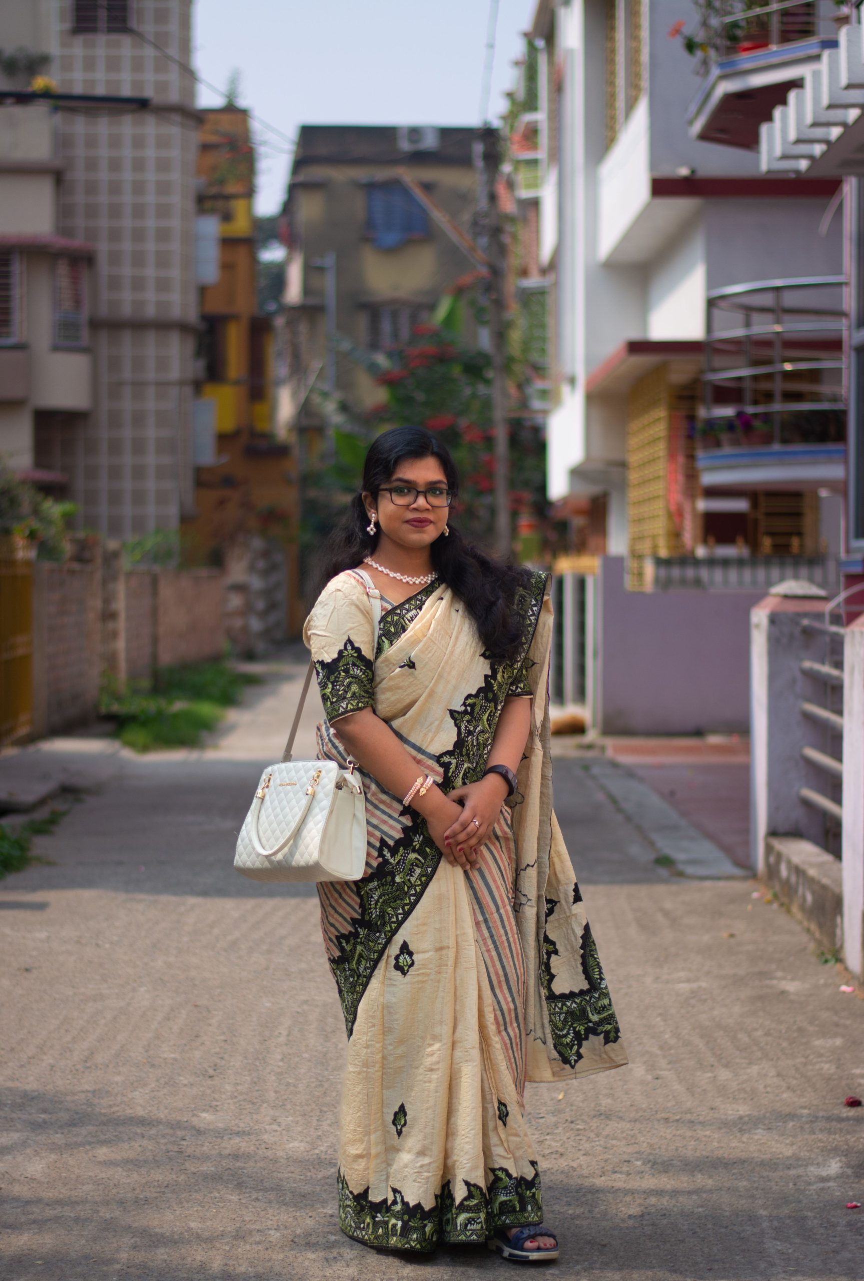 A woman in a traditional sari stands in an urban street, showcasing cultural fashion.